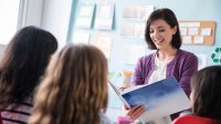 Teacher reads a book aloud to elementary students in class