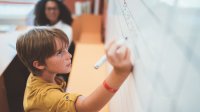 Photo of middle school student doing math on board