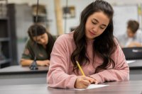 Students in a classroom writing on pieces of paper