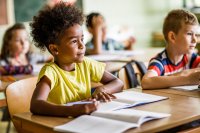 Elementary school student sitting at her desk, listening to her teacher