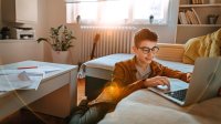 Teenage boy working on his laptop at home