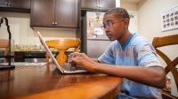 Student working on laptop at his kitchen table