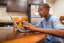 Student working on laptop at his kitchen table