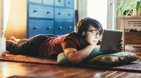 Teenage boy lying on floor looking at ipad