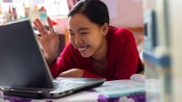 Asian teenage girl having video call with teacher for home schooling using laptop