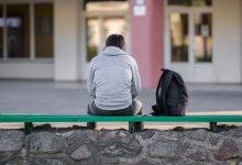 Teenager sits outside a school alone