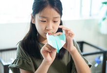 Young girl making a paper airplane at home