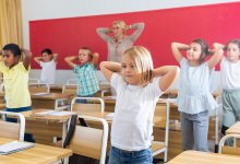 Elementary teacher and students stretch in classroom 