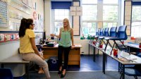 A teacher and administrator speak in a classroom