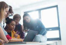 Photo of high school students looking at computer