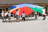 A group of elementary students playing with a colorful parachute during PE