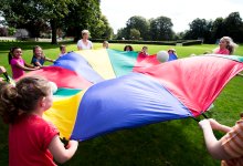 Teacher and students playing with parachute outside