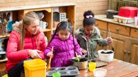 Pre-k students garden outside with teacher