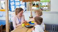 Photo of young students playing store with teacher