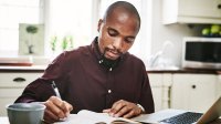 Man at home writing in notebook