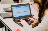 A student works on a coding project on her laptop in a classroom