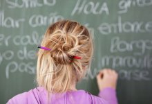 A girl works on a Spanish exercise on a blackboard.