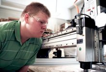 Boy wearing safety goggles working on a table saw