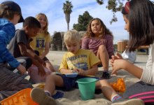 A group of fourth-grade students play with a peer with special needs in a sandbox during a field trip to a local playground in southern California. 