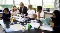 A teacher and students gather around a table in their classroom.