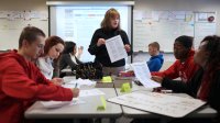 A teacher helping students with their writing in English class