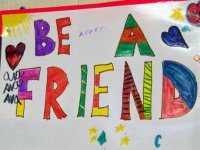 A poster pinned on the wall drawn by students that says "Be A Friend"