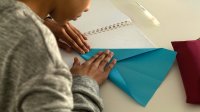 Child making paper plane at table