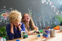 Two students laughing at a table while working on a science project.