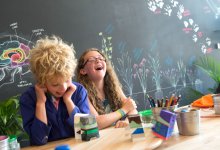 Two students laughing at a table while working on a science project.