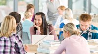 Groups of students discuss novels in their classroom.