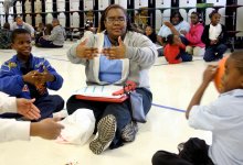 Teacher sitting on floor with students playing ball