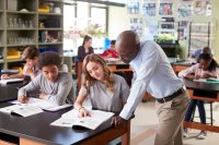 A teacher helping a student with a worksheet in science lab