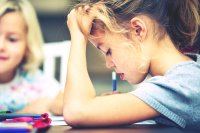 An elementary student working on an assignment, thinking hard