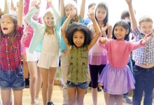 A group of elementary school students standing with their arms in the air.