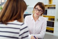 Female teacher engaged in discussion with a parent.