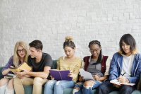 A diverse group of teens reading together on a bench