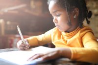 Profile of little girl writing at home.