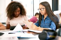 Two teenage schoolgirls using tablet computers in class.