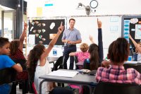 Kids raising hands in an elementary school class.