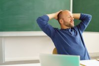 A teacher sitting at his desk with his eyes closed, relaxed