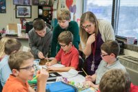 Teacher helping a group of elementary students in the classroom.