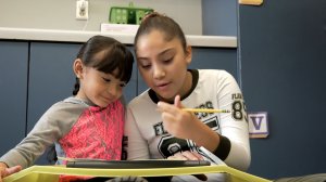 A photograph of an older student working with a younger student.