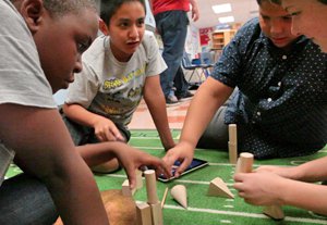 Three boys and teacher sitting on the floor around building blocks