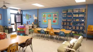 A classroom with large rectangular tables and a futon.