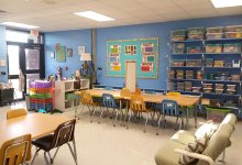 A classroom with large rectangular tables and a futon.