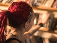 Older girl in the library reaching for a book off the shelf