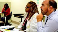 Teacher and principal at desks listening