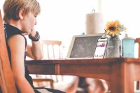 Elementary-aged boy watching a video of his teacher reading a book on a smartphone