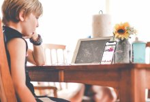 Elementary-aged boy watching a video of his teacher reading a book on a smartphone