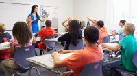 Students raise their hands in a class.